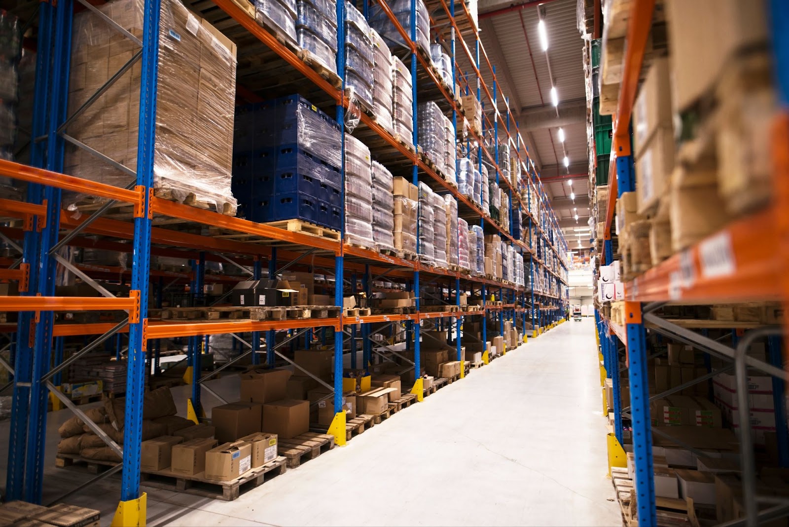 Large distribution warehouse with shelves stacked with palettes and goods