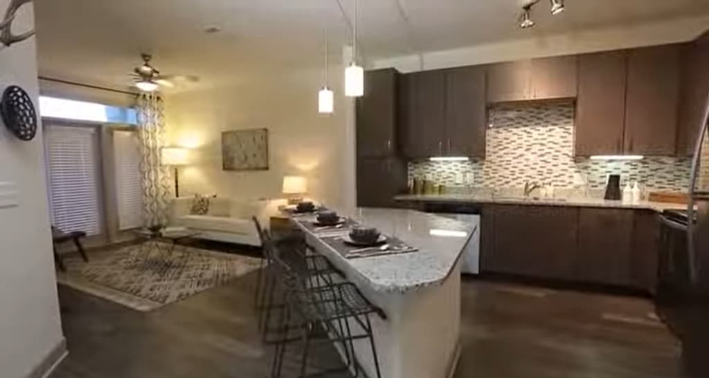 A sleek kitchen with bar seating and a spacious living area