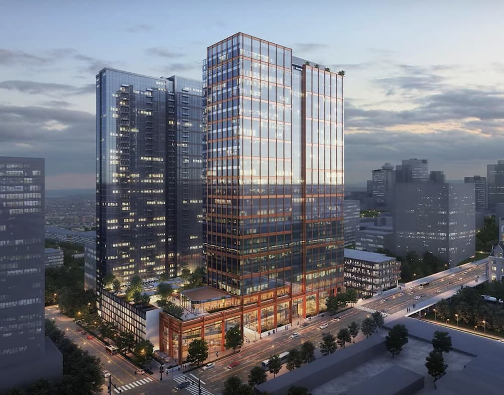 A modern glass skyscraper gleams at dusk in an urban skyline